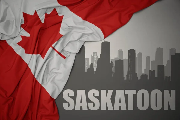 テキストを持つ都市の抽象的なシルエットサスカトゥーンは灰色の背景にカナダのカラフルな国旗を振っています — ストック写真