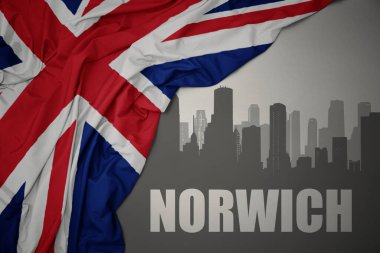 Kentin soyut silueti. Üzerinde Norwich yazıları var. Gri arkaplanda büyük Britanya bayrağı sallanıyor..
