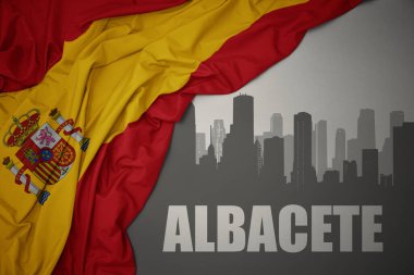 Kentin soyut silueti. Albacete, gri bir arkaplanda renkli ulusal İspanya bayrağı sallıyor..