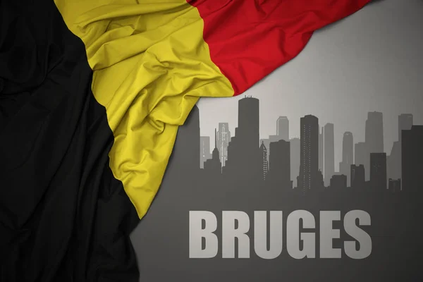 街の抽象的なシルエットとテキスト灰色の背景にベルギーのカラフルな国旗を振って近くのブルージュ — ストック写真
