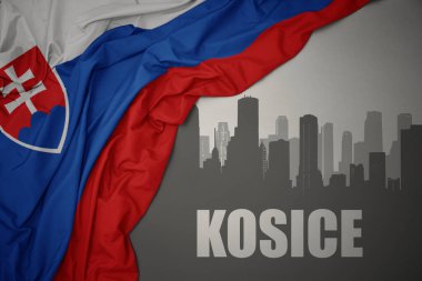 Şehrin soyut silueti ve gri bir arkaplanda renkli ulusal slovakya bayrağı dalgalandıran Kosice yazıları..