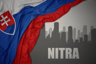 Şehrin soyut silueti ve gri bir arkaplanda renkli slovakya bayrağı sallayan Nitra metni..