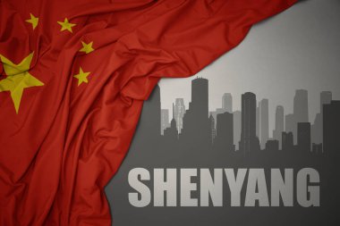 Şehrin soyut silueti, üzerinde Shenyang yazıları olan gri bir arkaplanda renkli bir Çin bayrağı sallıyor..
