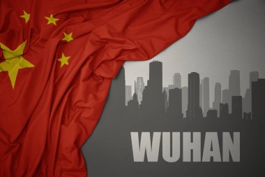 Şehrin soyut silueti ve gri arkaplanda renkli bir Çin bayrağı dalgalandıran Wuhan yazıları..