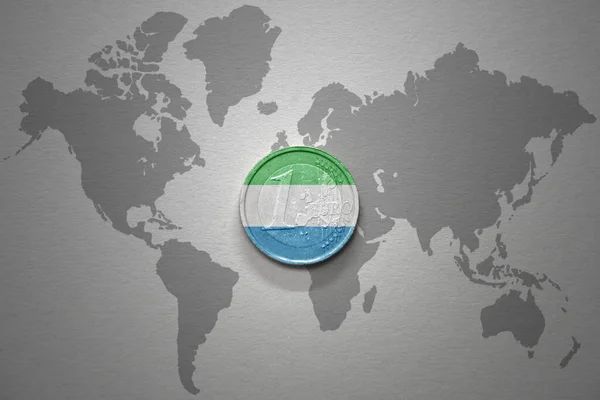 灰色の世界地図の背景にシエラレオネの国旗とユーロコイン 金融の概念 — ストック写真