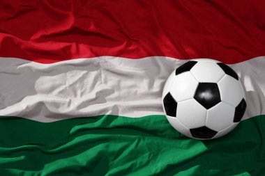Hungary arka planında sallanan ulusal bayrağın üzerinde eski, klasik bir futbol topu. 3B illüstrasyon