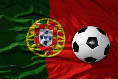 Portekiz 'in arka planında sallanan ulusal bayrak üzerinde eski, klasik bir futbol topu. 3B illüstrasyon