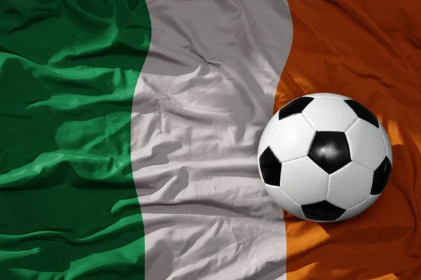 old, vintage football ball on the waveing national flag of ireland background. 3D illustration