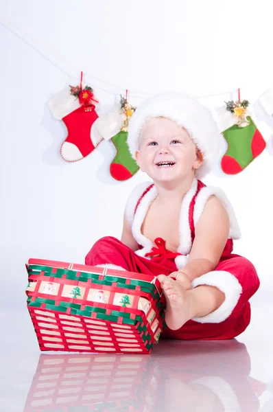Cute baby Santa Claus with garlands and Christmas basket — Stock Photo, Image