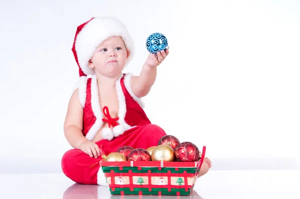 Cute baby Santa Claus with garlands and a basket of Christmas to — Stock Photo, Image