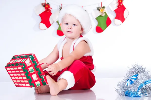 Cute baby Santa Claus with garlands and Christmas basket — Stock Photo, Image