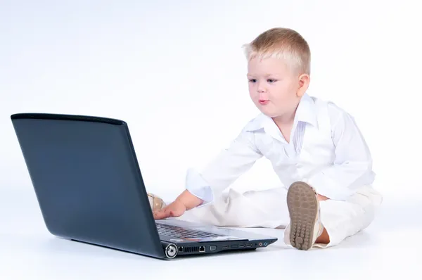 Little business boy in solid white suit sitting at notebook on — Stock Photo, Image