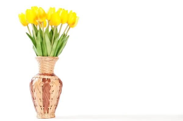 Yellow tulips in a wicker vase on a white background. — Stock Photo, Image