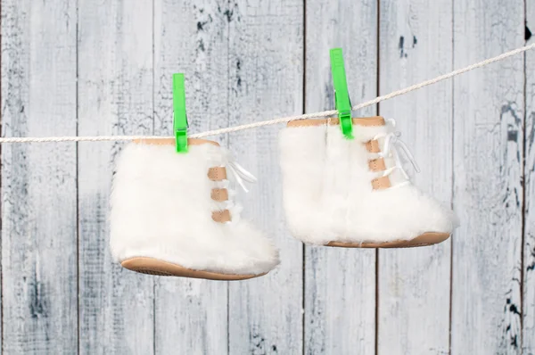Children's boots hanging on a clothesline.