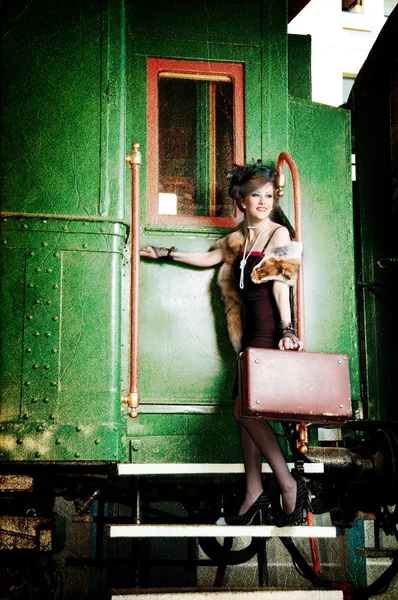Ρετρό κορίτσι με τη βαλίτσα κοντά το παλιό τρένο — Φωτογραφία Αρχείου