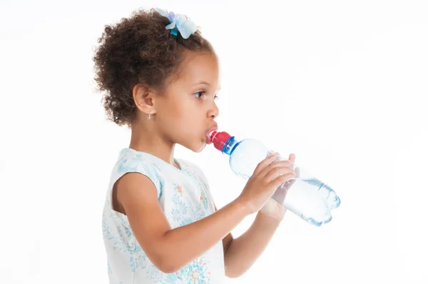 The little mulatto girl drinks water from a bottle. — Stock Photo, Image