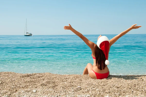 Girl on the beach in a Christmas hat. — Stock Photo, Image