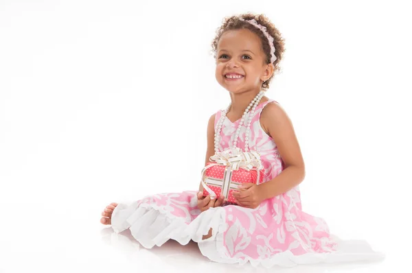 Glückliches kleines Mädchen mit einem Geschenk in Mulattahänden. — Stockfoto