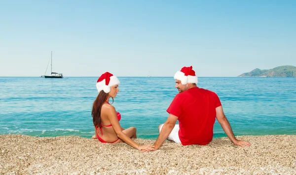 Férias de Natal à beira-mar. Menina com um cara vestindo santa claus . — Fotografia de Stock