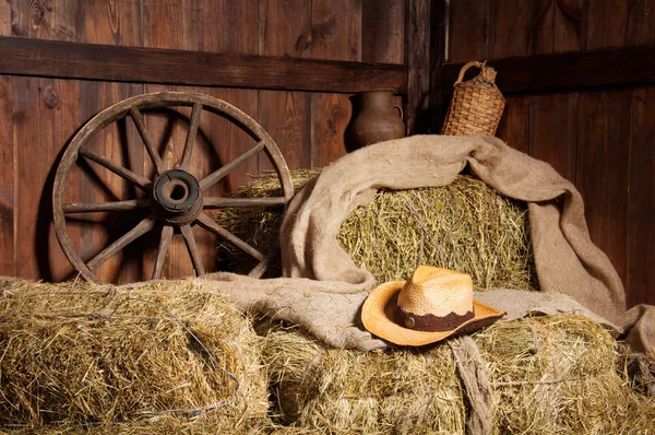 Interno di una fattoria rurale - fieno, ruota, cappello di cowboy . — Foto Stock