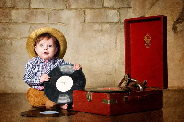 Kleine jongen zitten met een plaat in de buurt van de gramophone. — Stockfoto