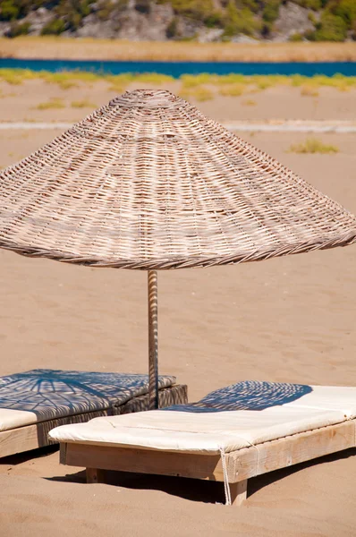 Ομπρέλες ξαπλώστρες και ινδικού καλάμου για αμμόφιλη παραλιακή. — Φωτογραφία Αρχείου
