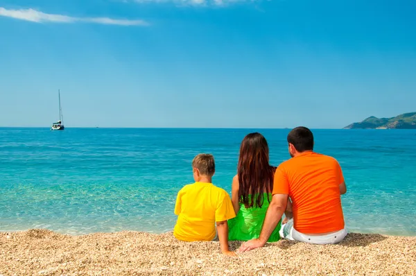 Famille heureuse : maman, papa et fils assis sur la plage, regardant au loin — Photo