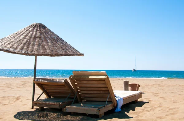 Tumbonas y sombrillas de ratán en la playa de arena . — Foto de Stock