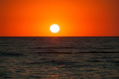Deniz ufukta turuncu günbatımı manzarası