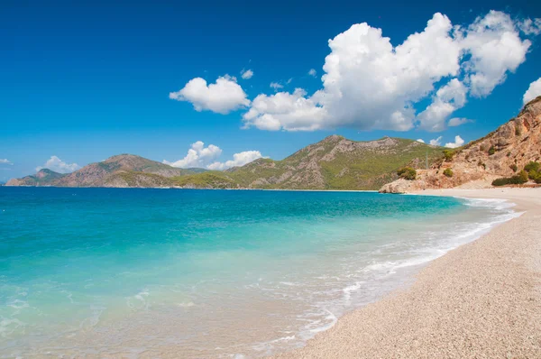 Schöne Brandung am Strand. Berge am Horizont. — Stockfoto