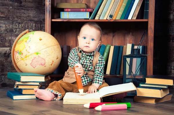 Cute baby boy sitting with globe, books and drawing pencils — Stock Photo, Image