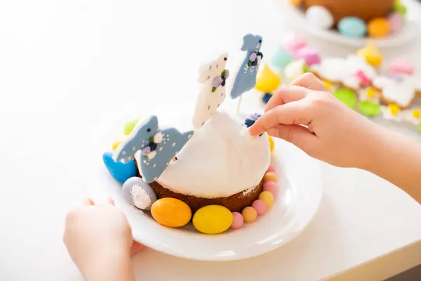 お祝いの装飾 砂糖のウサギの人形やカラフルな卵でイースターケーキを飾る子供の手のクローズアップ 高品質の写真 — ストック写真
