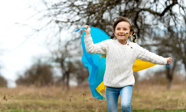 Sarı Mavi Kurdeleli Küçük Bir Kız Rüzgarda Dalgalanan Ukrayna Bayrağıyla — Stok fotoğraf