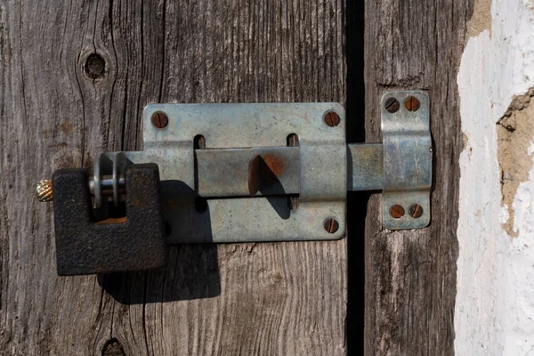Old padlock, latch on wooden door with cracked texture. Close-up. High quality photo