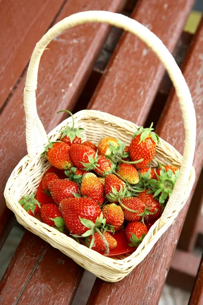 Frische Erdbeeren im weißen Korb auf der alten Bank — Stockfoto