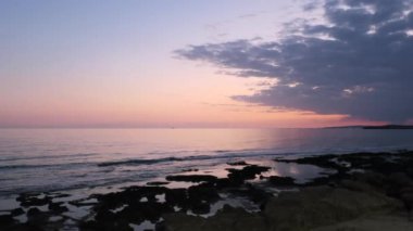 Güneşin Akdeniz 'deki romantik pembe yansıması Kıbrıs adasındaki Ayia Napa plajında