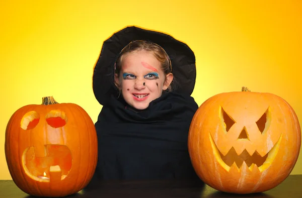 Ung flicka som en häxa med en pumpa på halloween. — Stockfoto