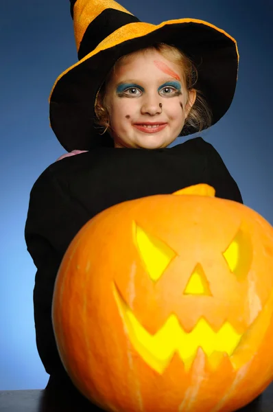 Ung flicka som en häxa med en pumpa på halloween. — Stockfoto