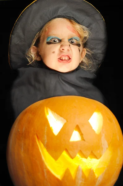 Fata tânără ca o vrăjitoare cu un dovleac de Halloween . — Fotografie, imagine de stoc