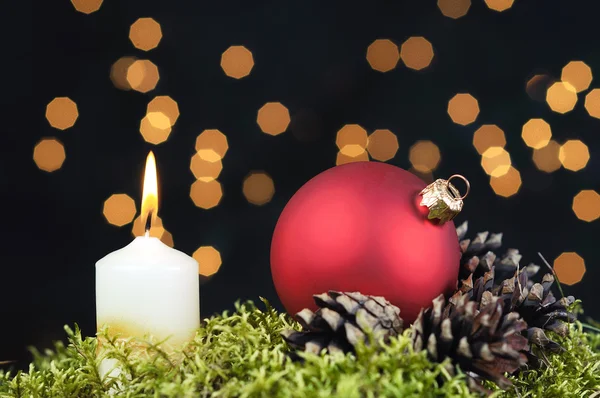 Red Christmas baubles and candle on black background of defocused golden lights. — Stock Photo, Image