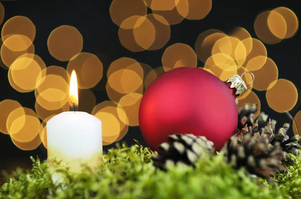 Red Christmas baubles and candle on black background of defocused golden lights. — Stock Photo, Image
