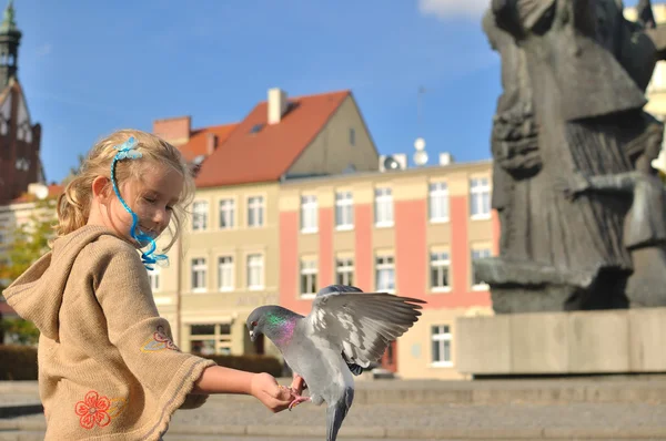 Little girl feeds doves in the city. — Stock Photo, Image