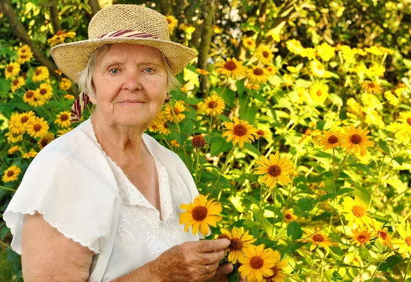 Mulher sênior com flores no jardim. — Fotografia de Stock