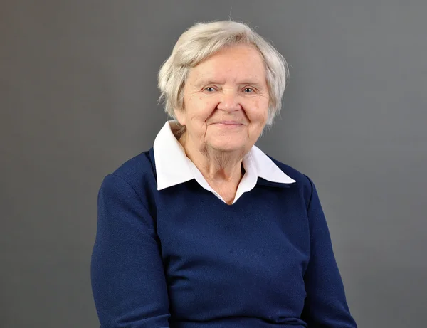 Senior happy woman with grey hairs against grey background. — Stock Photo, Image