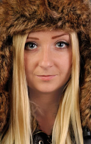 Young, pretty, blond woman in fur cap looks into the camera. — Stok fotoğraf