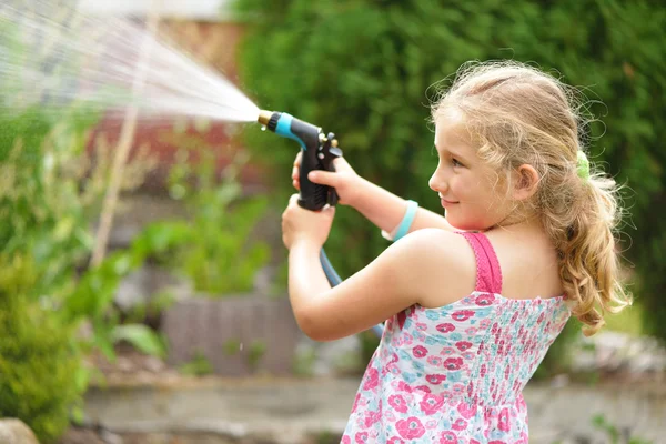 Giovane ragazza irrigazione piante in giardino. — Foto Stock