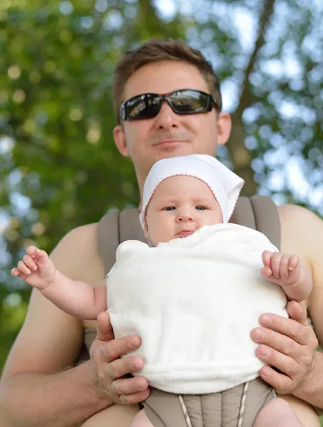 Lycklig far bär sitt barn i transportören. — Stockfoto