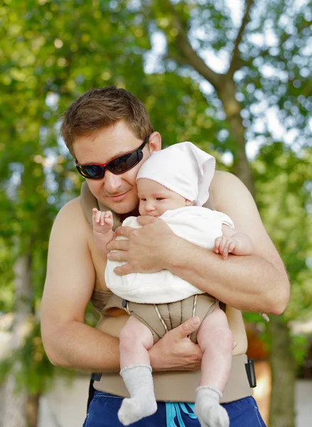 Pai feliz carrega seu bebê na transportadora . — Fotografia de Stock