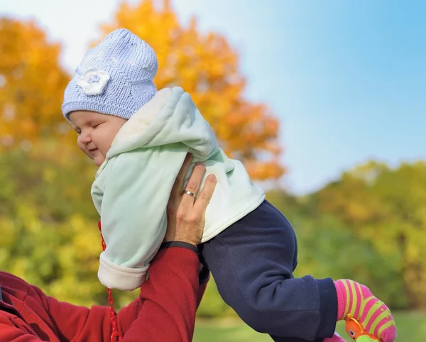 Gelukkig glimlachende baby opgehouden door zijn vader tegen de hemel. — Stockfoto