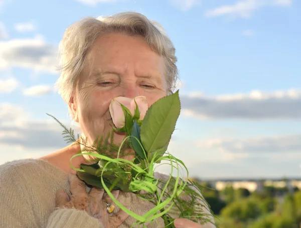 Senior woman smelling rose — Stock Photo, Image